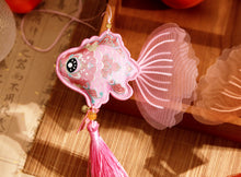 Load image into Gallery viewer, Decorative fish-shaped ornament with pink and gold details on a textured surface