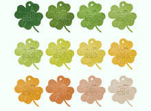 Load image into Gallery viewer, Set of eight clover-shaped calendars in different colors on a white background