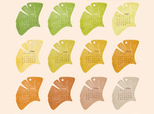 Load image into Gallery viewer, Calendar design on leaf-shaped cards in various colors on a beige background
